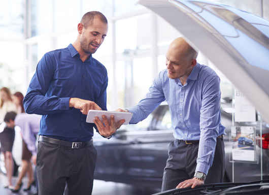 Automotive dealership salesman showing customer ReverseRisk on tablet