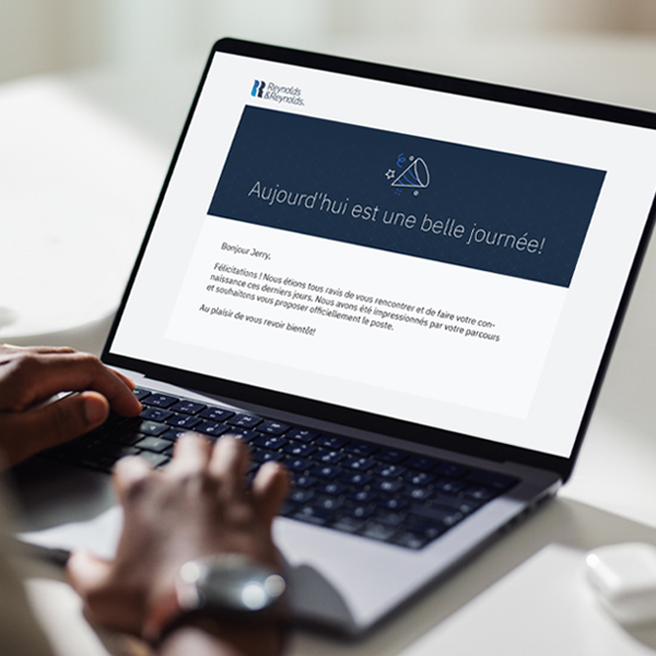 Un jeune homme regarde l'écran d'un ordinateur portable avec un courriel d'offre d'emploi de Reynolds.